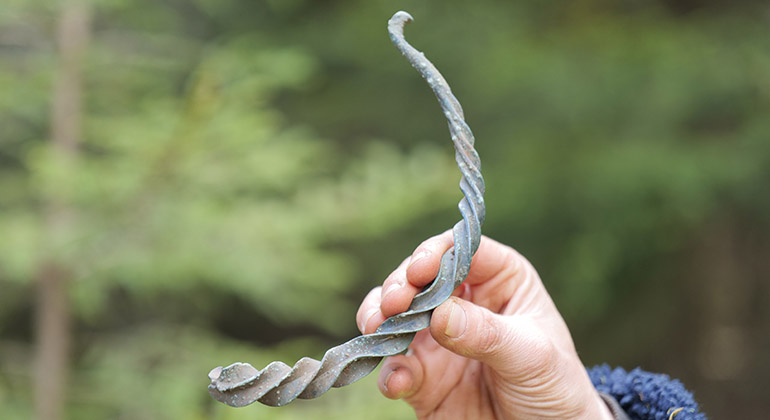 Fotografie eines sog. Wendelrings. Dieser Halsring weist ein in sich gedrehtes Spiralmuster auf, das sich zu den Enden hin verjüngt.