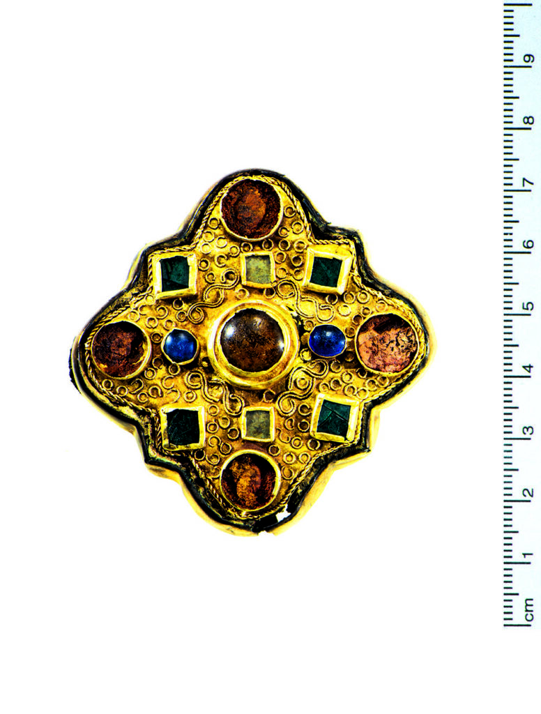 Vierpassfibel mit farbigen ­Glasein­lagen in aufgelöteten Fassungen, dazwischen filigrane Ornamente aus feinem Golddraht. Breite 5,8 cm.
