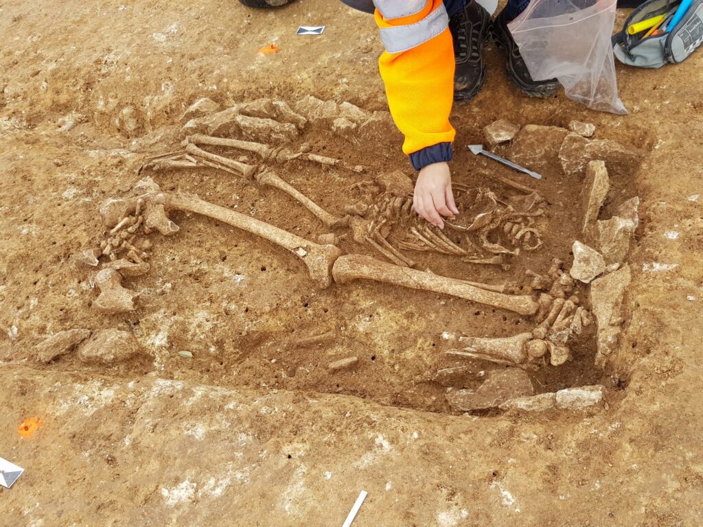 Mittelalterliche Bestattung: Das Skelett eines Kindes liegt zwischen den Beinen eines bestatteten Erwachsenen.